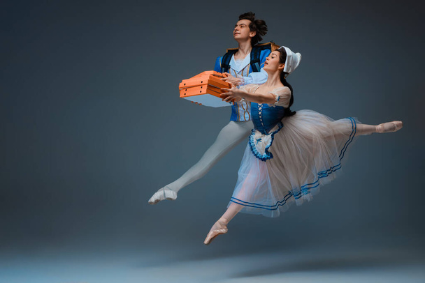 Young and graceful ballet dancers as Cinderella fairytail characters hurrying up with pizza like deliveryman - Foto, imagen