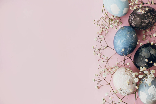 Stilvolle Ostereier und Frühlingsblumen umranden pinkfarbenes Papier flach, Platz für Text. Moderne, natürlich gefärbte blaue und marmorfarbene Ostereier. Frohe Ostern. Grußkarten-Vorlage - Foto, Bild