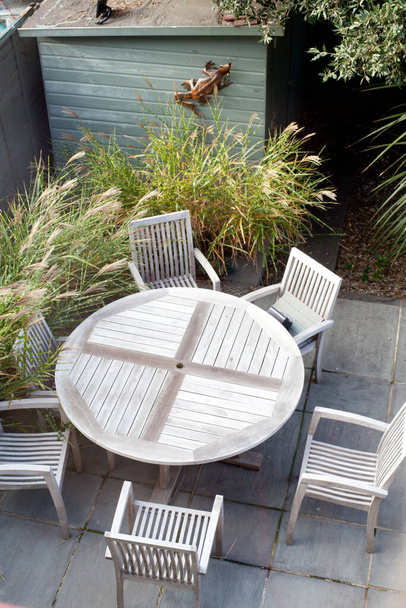 mesa de jardín de madera y sillas en un pequeño jardín urbano moderno en el patio con hierbas y cobertizo
 - Foto, Imagen
