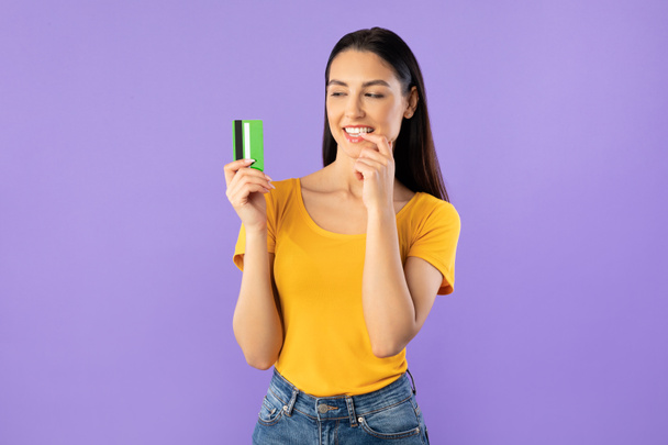 Mujer joven sosteniendo tarjeta de crédito y soñando
 - Foto, imagen