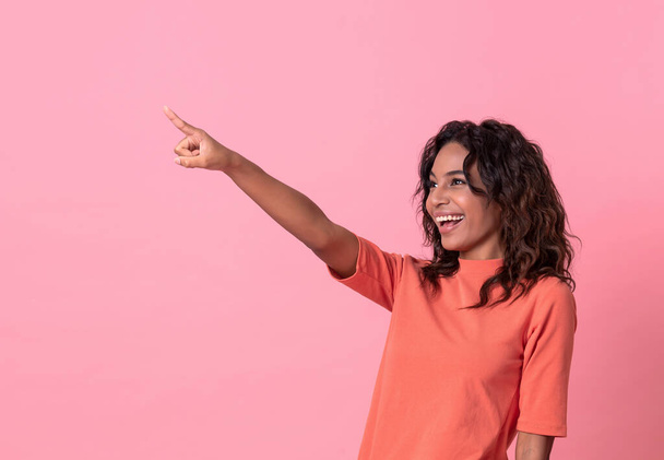 Heureuse jeune femme sa main pointue sur fond de bannière rose avec espace de copie
. - Photo, image