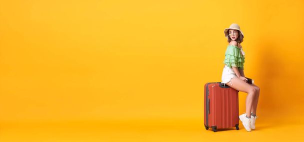 Yaz kıyafetleri içinde neşeli genç bir kadın elinde bavuluyla arka planda sarı afişle fotokopi çeken bir pasaport taşıyor.. - Fotoğraf, Görsel