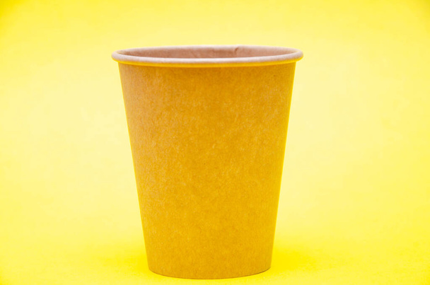 コーヒー、紅茶用の茶色い紙コップ、黄色の背景に環境材料からの飲み物。マクロの小さなカップが右側にあります。フロントビューとトップビュー、下部に表示されます。左側のテキストの場所 - 写真・画像