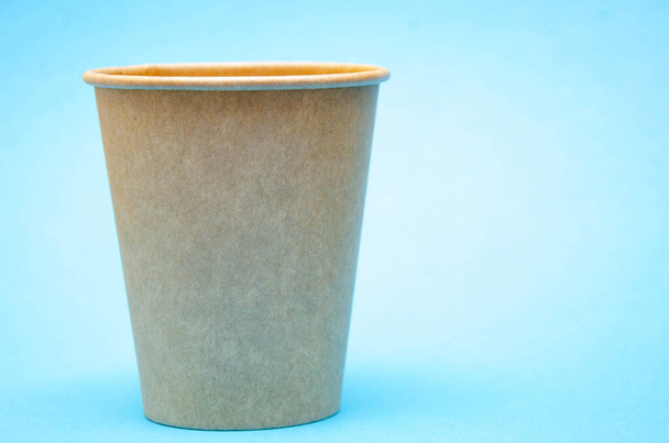 Бумажный стаканчик для кофе, чая, напитка из экологических материалов на синем фоне. Маленькая чашка в макро справа. Вид спереди и вид сверху, вид снизу. Место для текста слева
 - Фото, изображение