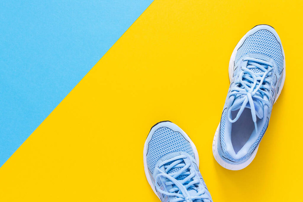 Niebieskie trampki odizolowane na żółto-niebieskim tle, sezonowe buty do chodzenia i uprawiania sportu, przestrzeń do kopiowania, widok z góry - Zdjęcie, obraz