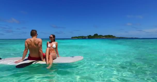Preciosa pareja en tabla de surf surfeando en el mar claro en Bali - Metraje, vídeo