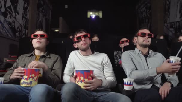 Three friends are watching a movie and eating popcorn - Footage, Video