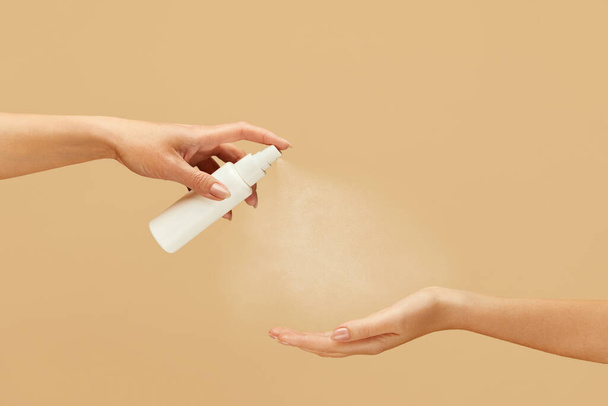 Hygiene. Female Hands Using Spray Antiseptic On Beige Background. Daily Routine With Antibacterial Products For Virus Prevention And Staying Healthy.  - Фото, изображение