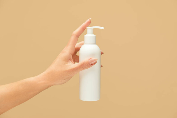 Personal Hygiene. Female Hand Holding Gel Sanitizer Bottle On Beige Background. Washing Hands For Virus Prevention And Staying Healthy.  - 写真・画像