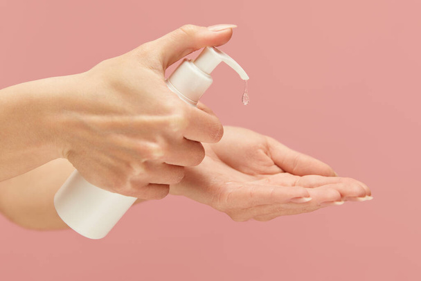 Hand Hygiene. Female Applying Sanitizer On Her Palm Against Pink Background. Cleaning Hands For Virus Prevention And Staying Healthy. - Foto, afbeelding