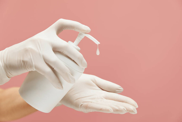 Personal Hygiene. Hands In White Gloves With Bottle Of Soap On Pink Background. Daily Routine With Antibacterial Products For Virus Prevention And Staying Healthy.  - Foto, Imagem