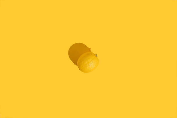 Whole lemon on a yellow background with a hard shadow. The concept of summer, fruits, vitamins. - Fotografie, Obrázek