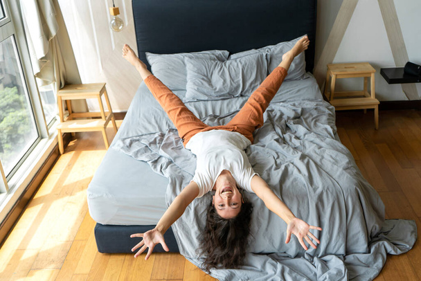 Beautiful young brunette girl fooling around on the bed. View from above. Good mood. - Fotoğraf, Görsel