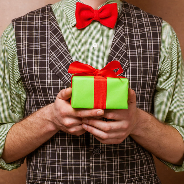 Guy holding a gift in a suit and bow tie - Фото, изображение