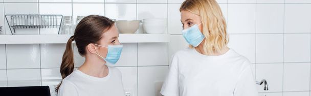 imagen horizontal de hermanas con máscaras médicas mirándose
 - Foto, Imagen