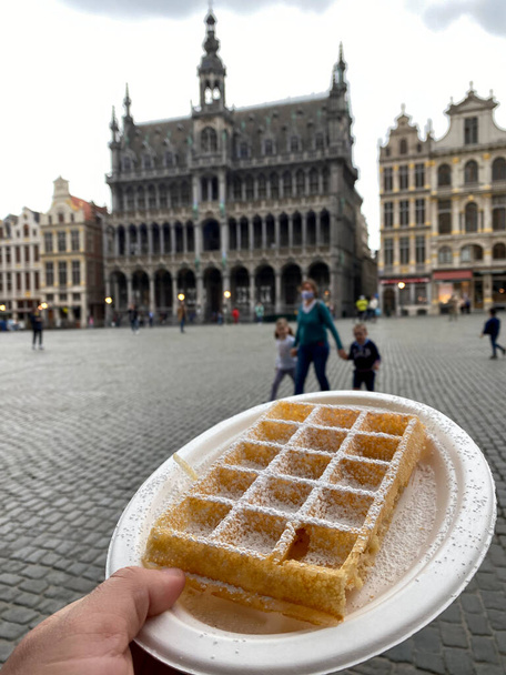 A man holds a Waffle (Gaufre) in Grand-Place in Brussels, Belgium May 24, 2020. - Photo, Image
