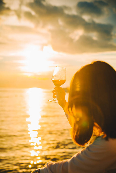 woman drink wine at sea beach looking on sunset. summer vacation. - Photo, Image