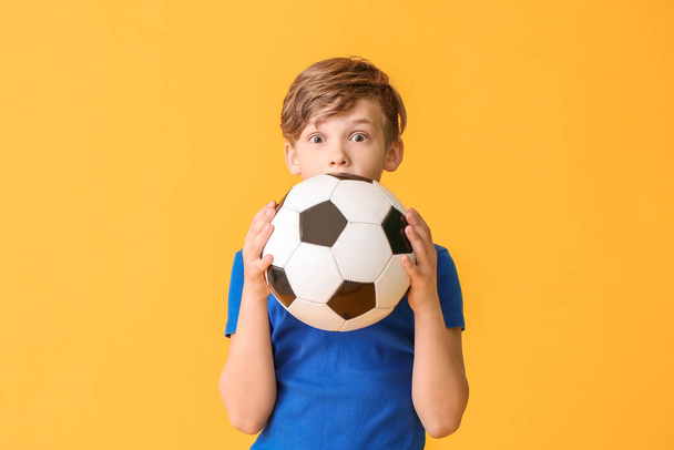 Cute little boy with soccer ball on color background - Fotó, kép