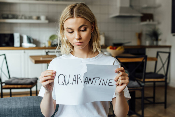 Beautiful young woman tearing card with quarantine lettering at home  - Foto, afbeelding