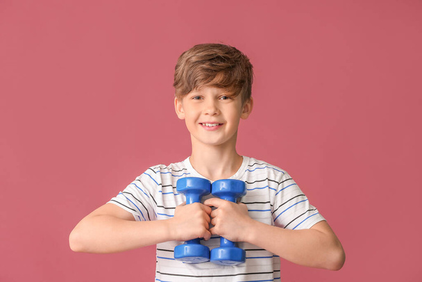 Sporty little boy with dumbbells on color background - 写真・画像