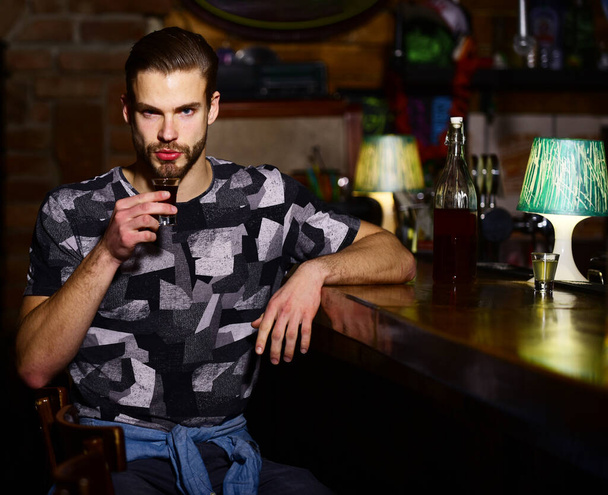 Man with beard sits in bar on blurred background. - Valokuva, kuva