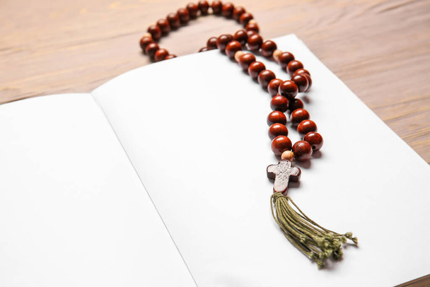 Holy Bible and rosary beads on wooden background, closeup - Photo, Image