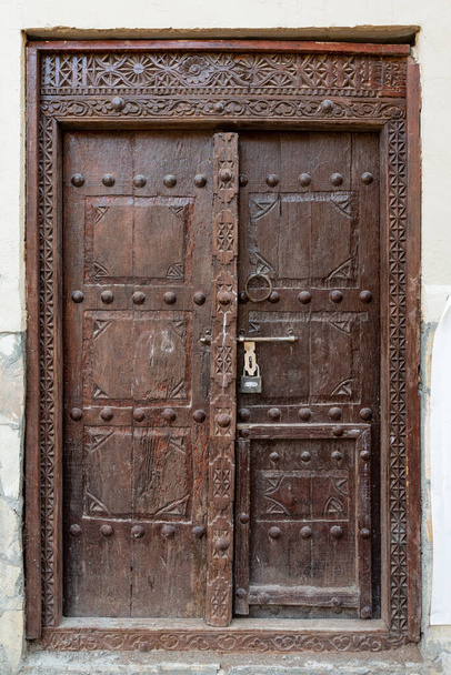 Traditionally carved Omani wooden door in dark brown color, seen in Nizwa - Photo, Image