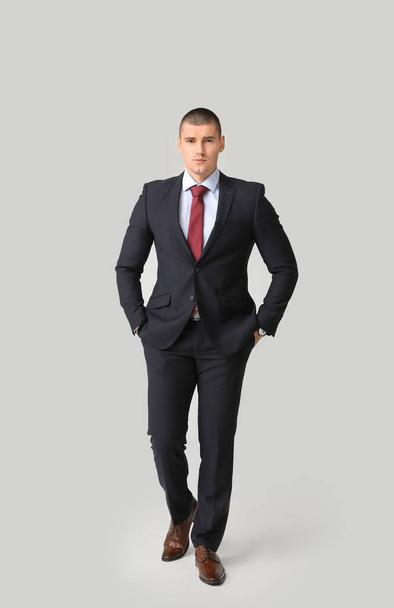 Knappe jongeman in elegant pak op lichte achtergrond - Foto, afbeelding