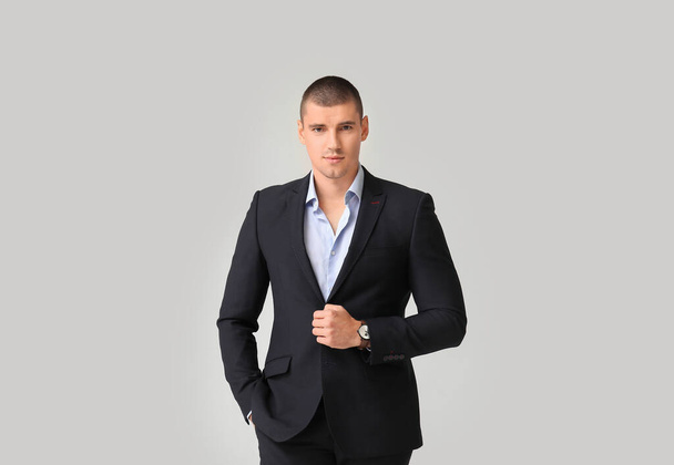 Schöner junger Mann im eleganten Anzug auf hellem Hintergrund - Foto, Bild