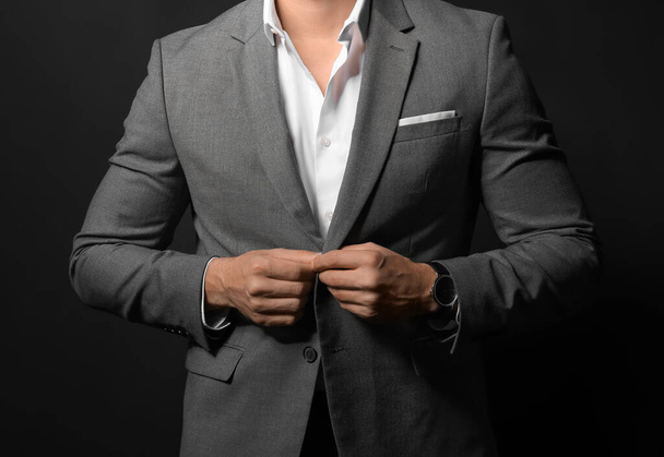 Handsome young man in elegant suit on dark background - Foto, imagen