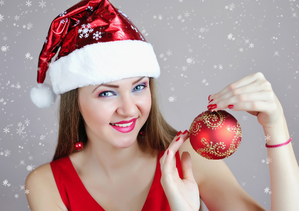 Attractive young woman holding red Christmas ball - 写真・画像
