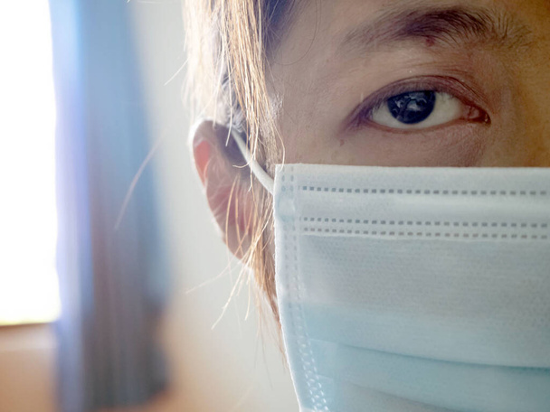 Colseup Auge der Krankheit Frau trägt Hygienemaske zum Schutz vor der Krankheit, sieht mit hoffnungslosem Gefühl, verschwommenes Licht herum - Foto, Bild