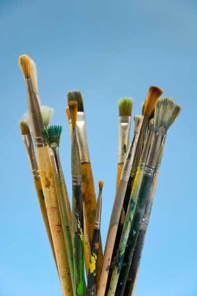Well used artists paintbrushes on a blue background - Photo, Image