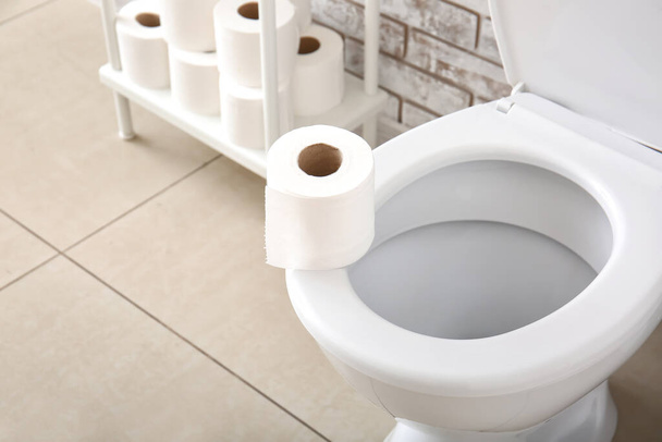 Toilet bowl and rolls of paper in restroom - Фото, изображение