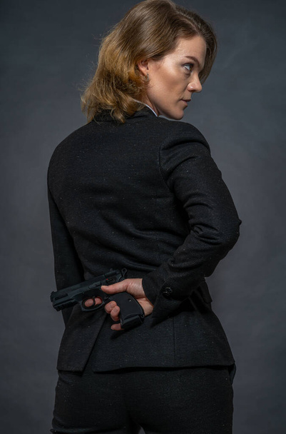 arme à la main derrière le dos d'une femme en costume
 - Photo, image
