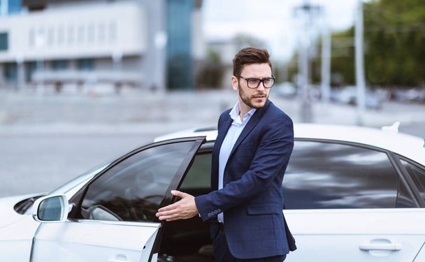 Fiducioso uomo d'affari che scende dalla sua auto in città urbana
 - Foto, immagini