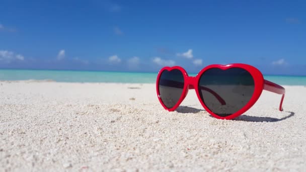 imagens de óculos de sol em forma de coração na praia de areia branca e belas ondas no fundo,  - Filmagem, Vídeo