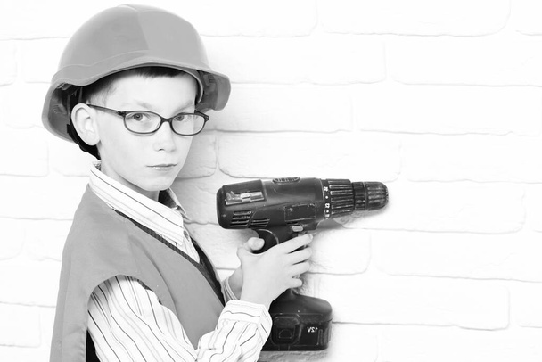 young cute builder boy on white brick wall background, copy space - Fotó, kép