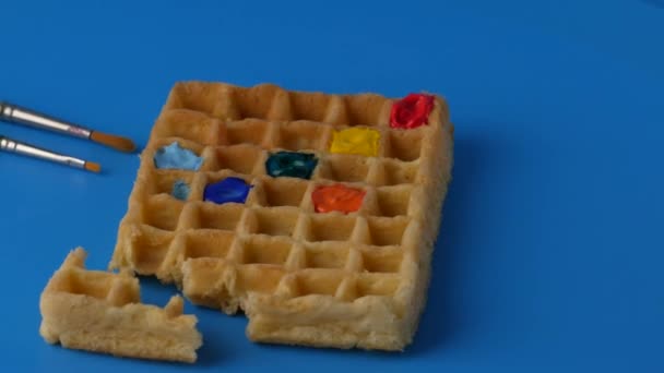 Rotating sweet colored belgian waffles on a blue background. - Felvétel, videó