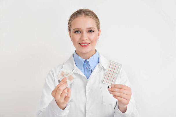 Женщина-гинеколог с различными контрацептивами на белом фоне
 - Фото, изображение