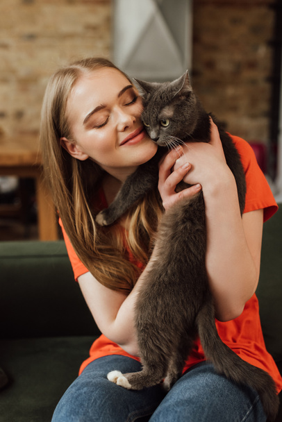 vrolijk meisje met gesloten ogen houden in armen pluizig kat  - Foto, afbeelding