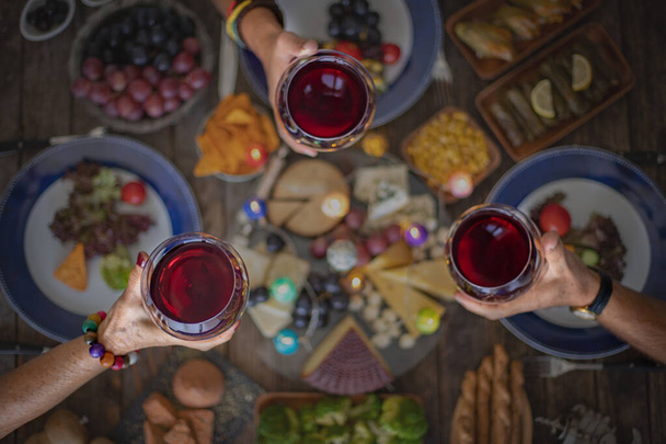 Family dinner for a celebration with red wine and cheers. Top view of a family dinner (meal) with togetherness - Fotografie, Obrázek
