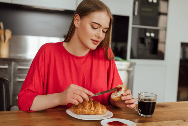 attractive girl holding knife with sweet jam near tasty croissant  - Fotoğraf, Görsel