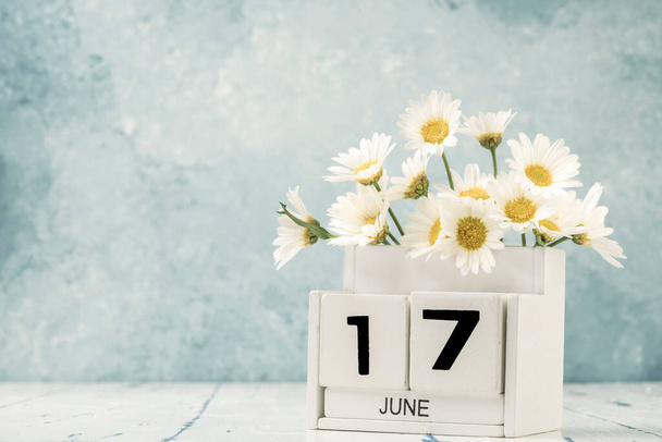 White Cube Kalender für Juni dekoriert mit Gänseblümchen Blumen auf blauem Hintergrund mit Kopierraum - Foto, Bild