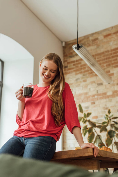 selective focus of cheerful woman holding cup of coffee  - Фото, зображення