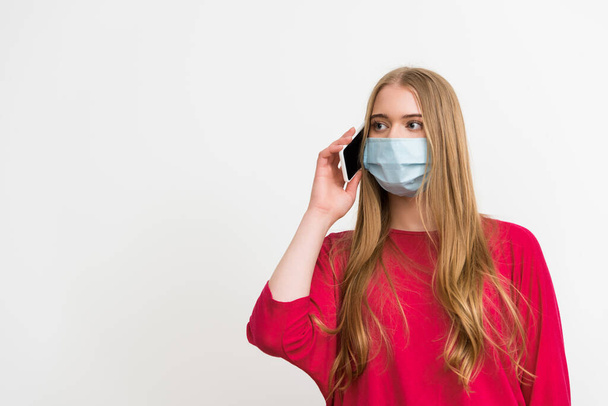 young woman in medical mask talking on smartphone isolated on white  - Foto, Imagem