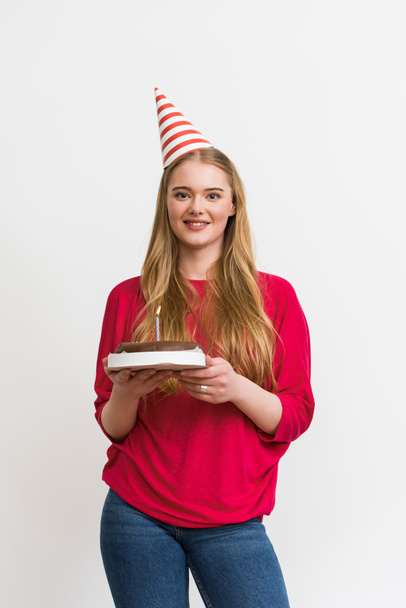bella ragazza in berretto partito sorridente e tenendo torta di compleanno isolato su bianco
  - Foto, immagini