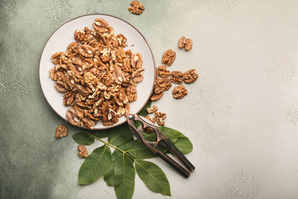 Plate with tasty walnuts on color background - Foto, Bild