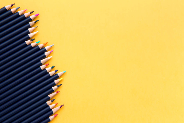 Color pencils lie in row on yellow background. Free space for text. Concept art, drawing, learning, business. - Photo, image
