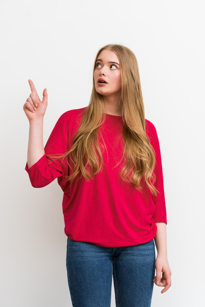 surprised girl pointing with finger while looking up isolated on white - Fotoğraf, Görsel